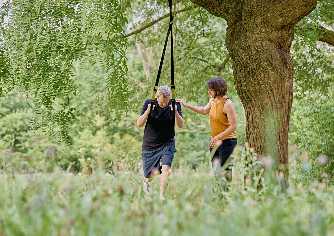 Sarah Hänggi begleitet einen Kunden beim TRX-Personal-Training im Park in Basel